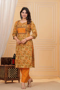 Woman wearing a mustard yellow floral handblock printed cotton kurta with orange zigzag pants set by Doriya Jaipur.